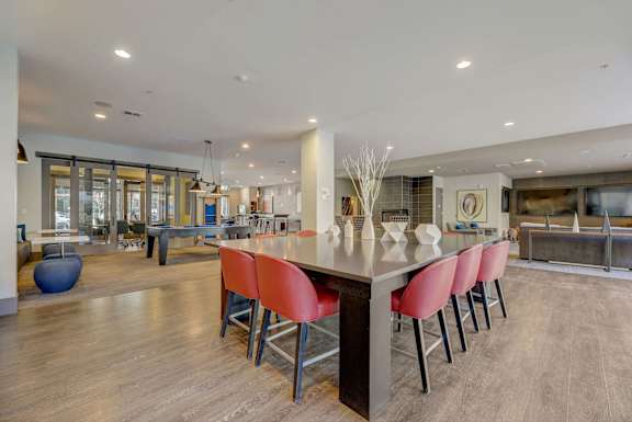 A modern kitchen with a long island and red chairs. at Regatta Sloans Lake Apartments, Denver, 80204