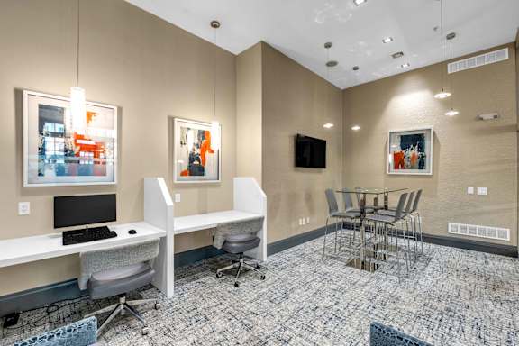A room with a desk, chairs, and a television.