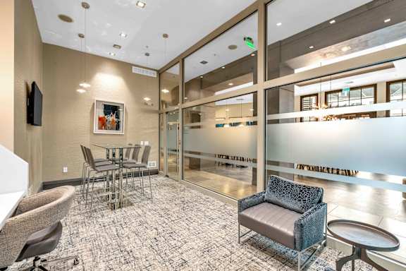 A modern waiting room with a glass wall and comfortable seating.