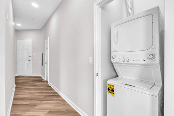 A white washing machine is in a narrow hallway.