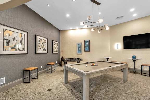 A room with a pool table and a TV on the wall.