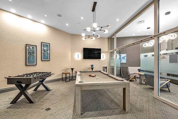 A room with a pool table, foosball table, and air hockey table.