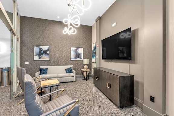 A modern living room with a grey sofa, a wooden coffee table, and a flat screen TV mounted on the wall.