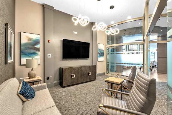 A modern living room with a grey sofa, a wooden cabinet, and a flat screen TV.