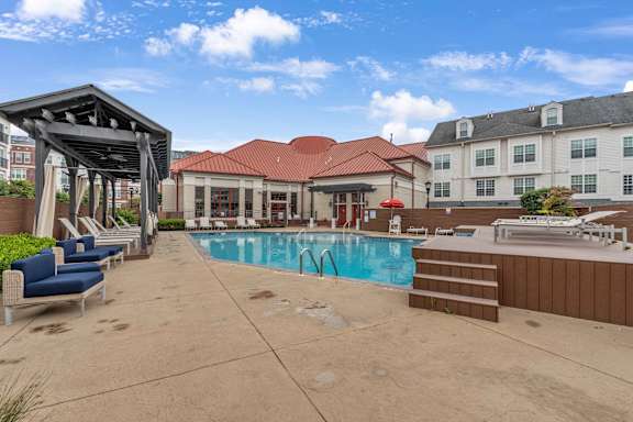 A pool area with a red-roofed building and lounge chairs.