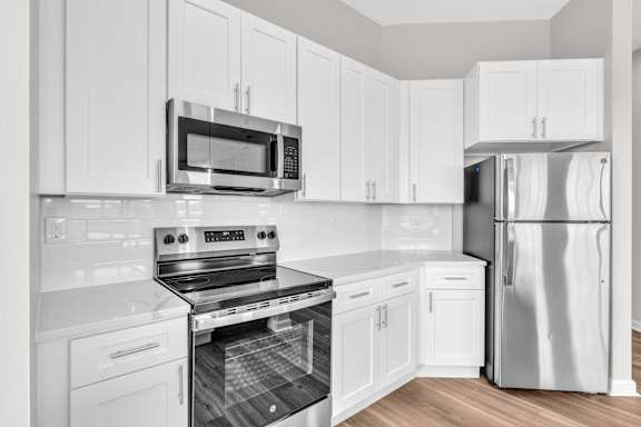 A modern kitchen with white cabinets and stainless steel appliances.