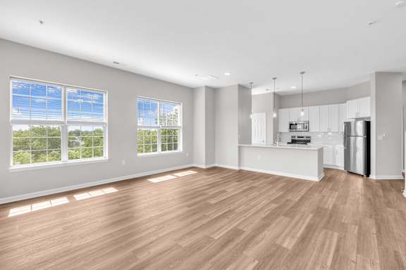 A spacious room with wooden flooring and large windows.