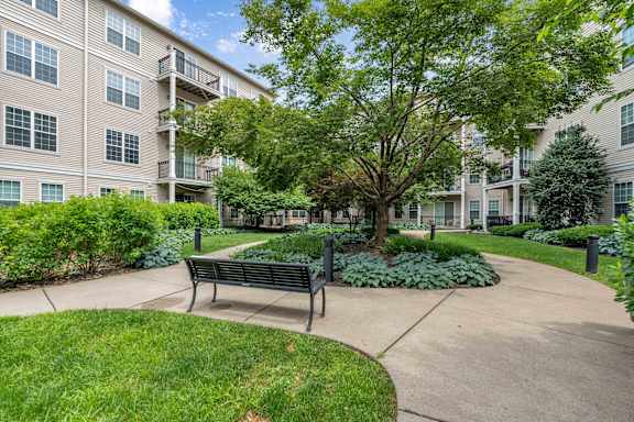 A bench is situated in the middle of a grassy area in front of a building.