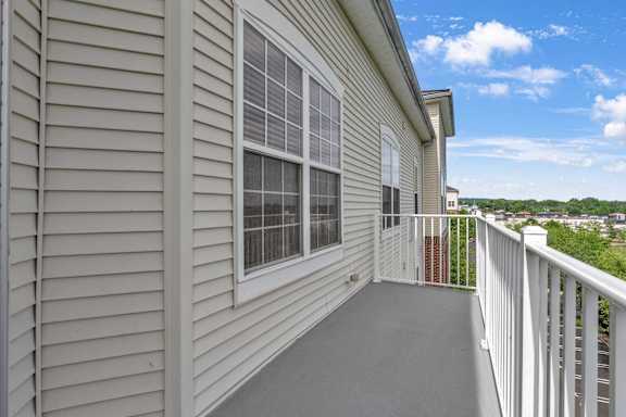 A balcony with a white railing and a sliding glass door.