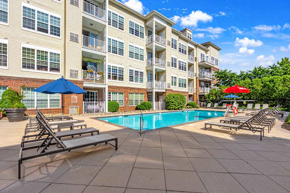 A large apartment complex with a pool and sun loungers.