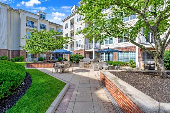 A sunny day at a residential complex with a well-maintained garden and seating area.