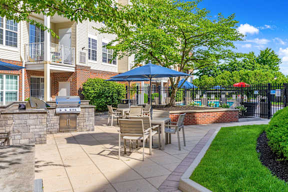 A patio with a table and chairs is surrounded by a black fence.