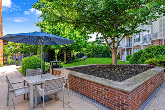A patio with a table, chairs, and a blue umbrella.