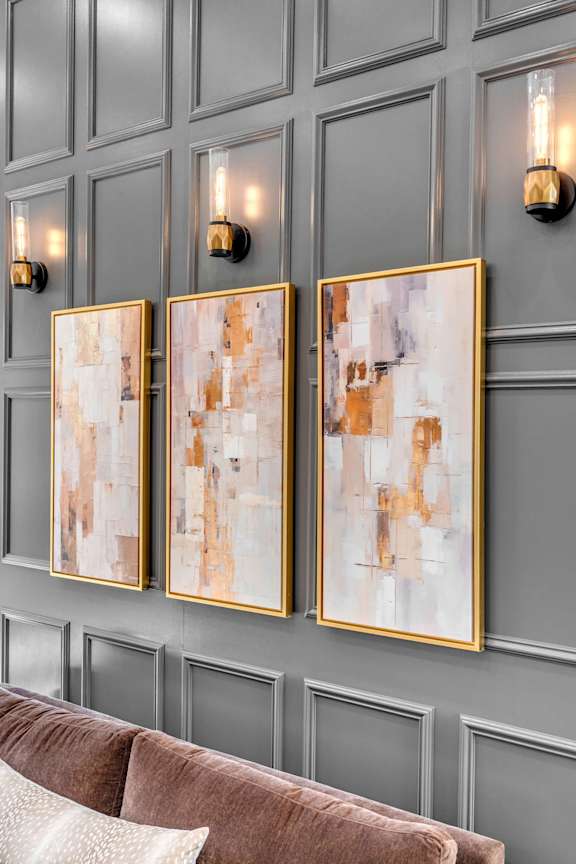 Three framed artworks hang on a wall above a couch.