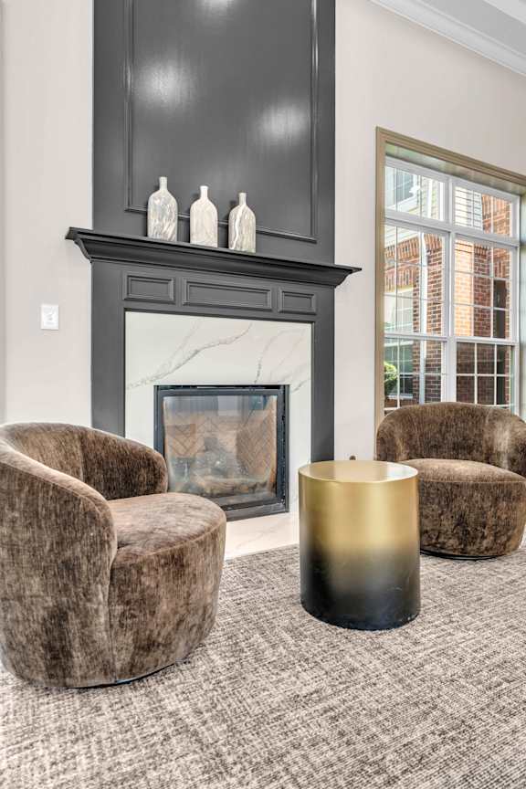 A living room with a fireplace and two chairs.