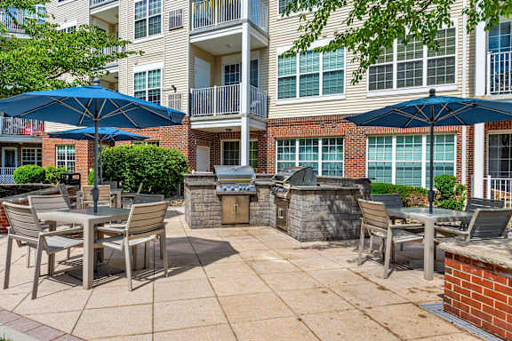 A patio with chairs and umbrellas in front of a brick building.
