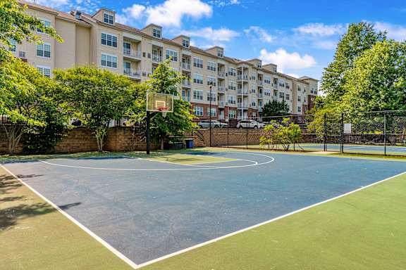 A basketball court is located in front of apartment buildings.