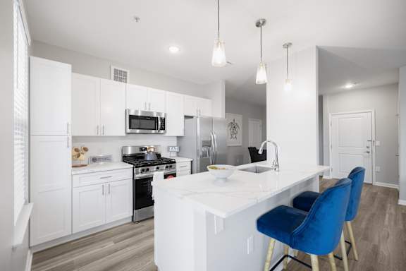 A modern kitchen with a white countertop and blue chairs.