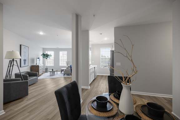 A modern living room with a black chair and a white vase on a woven tray.