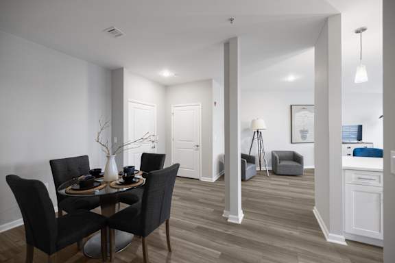 A dining room with a table set for two and a kitchen area in the background.