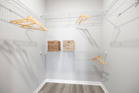 A white pantry with two shelves and hangers.