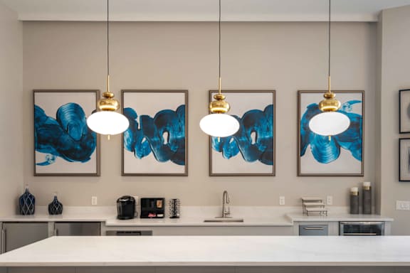 Three blue and white paintings hang on a wall above a kitchen counter in the clubhouse at Harbor Pointe Apartments, Bayonne