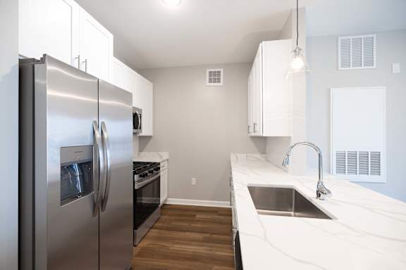 A modern kitchen with a stainless steel refrigerator and a marble countertop.