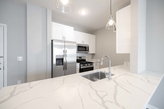 A kitchen with a marble countertop and stainless steel appliances.
