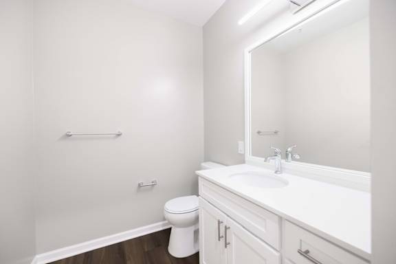 A white bathroom with a toilet, sink, and mirror.