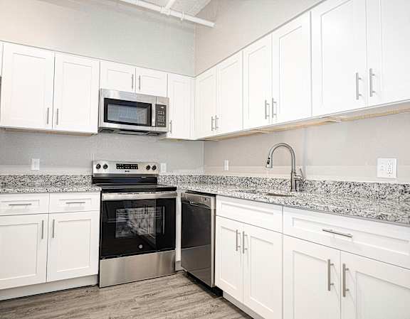 Modern kitchen with granite countertops and white cabinets at 222 Saratoga Apartments, Baltimore, MD 21202
