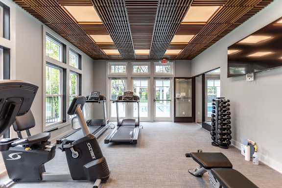 A gym with treadmills, exercise bikes, and weights.