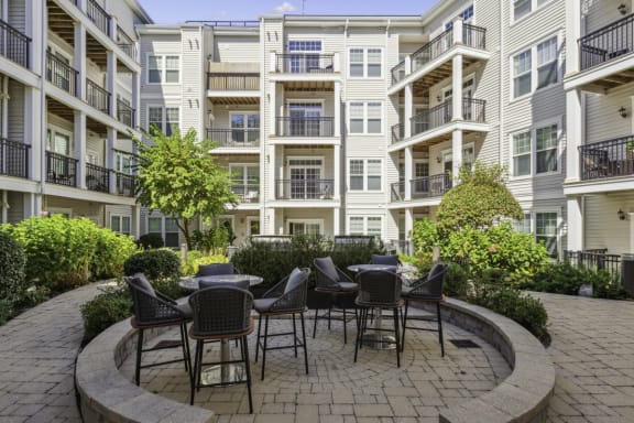 a patio with tables and chairs in front of an apartment building at Metro 303, New York, 11550