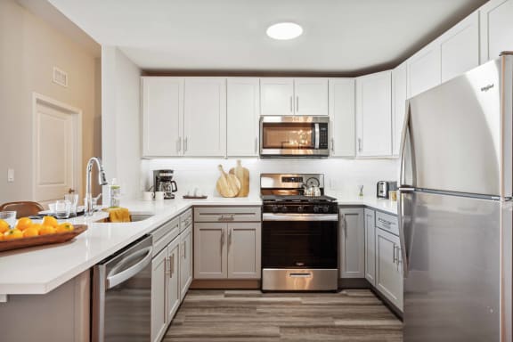 a kitchen with stainless steel appliances and white cabinets at Metro 303, New York, 11550