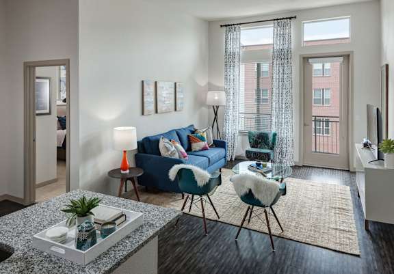 A living room with a blue couch, a chair, and a table with a plant on it at Regatta Sloans Lake Apartments, Denver, Colorado