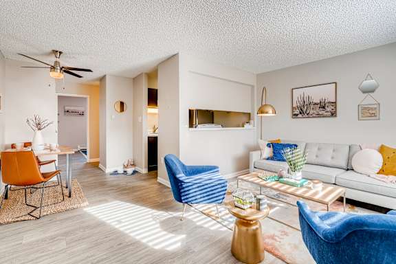 A living room with a white couch, blue armchair, and a coffee table at Mountain Vista Apartments, Colorado, 80228