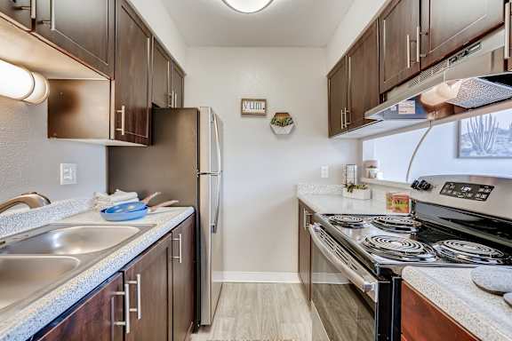 A kitchen with a stove top oven and a refrigerator at Mountain Vista Apartments, Lakewood