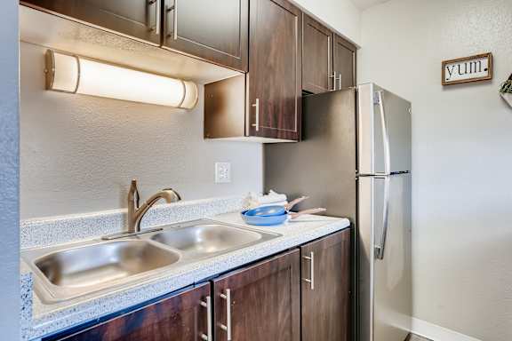 A kitchen with a sink, refrigerator, and cabinets at Mountain Vista Apartments, Colorado