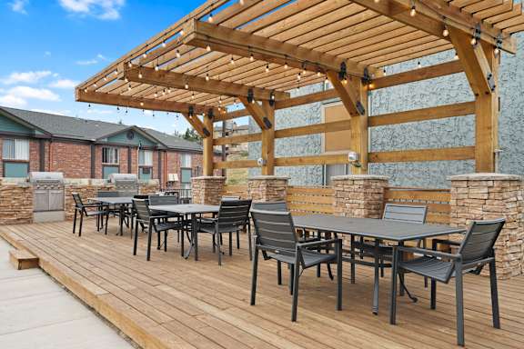 A wooden deck with a table and chairs under a pergola at Mountain Vista Apartments, Lakewood, Colorado
