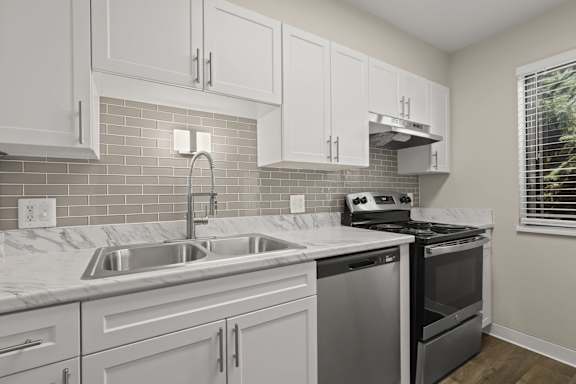 A kitchen with white cabinets and a stainless steel dishwasher.