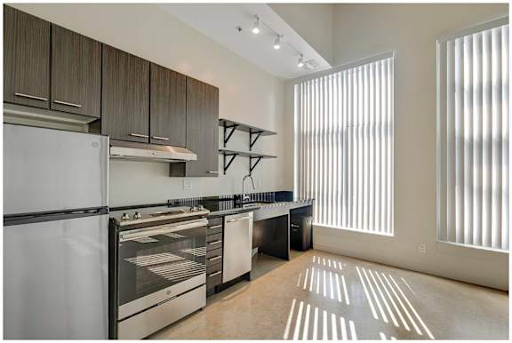 A modern kitchen with stainless steel appliances and wooden cabinets. at RiDE at RiNo Apartments, Denver, CO, 80216