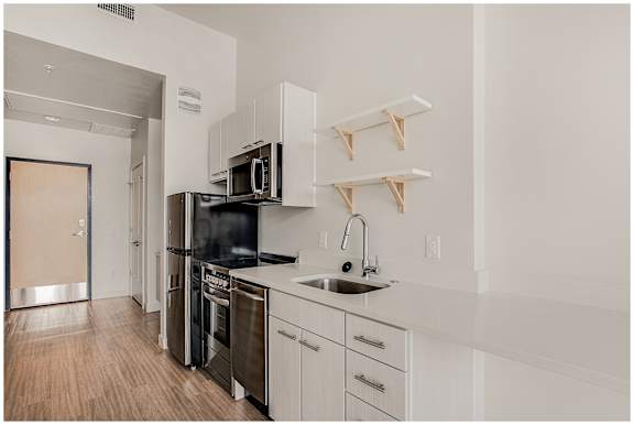 A kitchen with white cabinets and a black stove top oven. at RiDE at RiNo Apartments, Denver