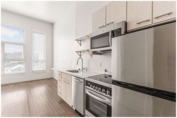 A kitchen with a stainless steel refrigerator, oven, and sink. at RiDE at RiNo Apartments, Denver, Colorado