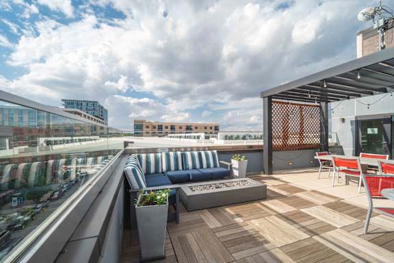 A rooftop patio with a blue couch and wooden deck at Regatta Sloans Lake Apartments, Colorado