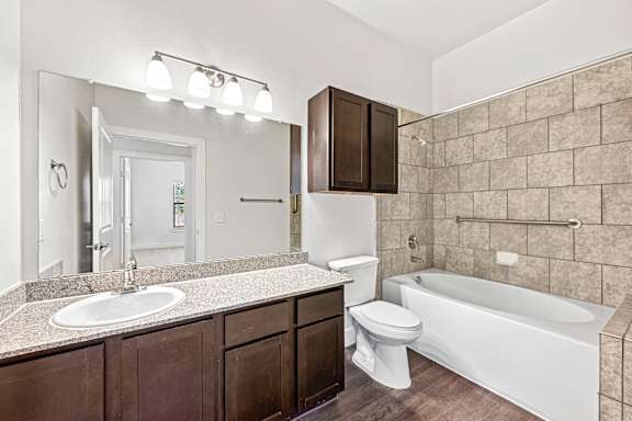 White bath tub along with wooden storage at The Laurel at Vintage Park 55+ Apartments, Tomball Texas