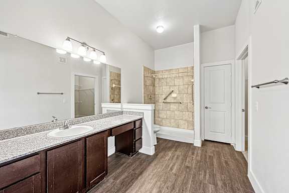 Bathroom with sink, mirror, and wooden floors at The Laurel at Vintage Park 55+ Apartments, Tomball