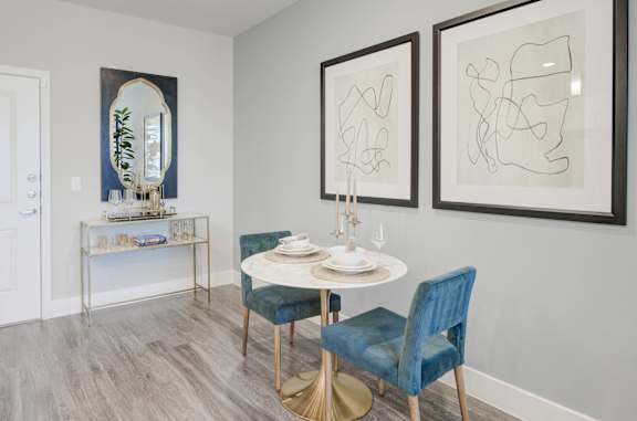 A dining room with a round table and blue chairs.