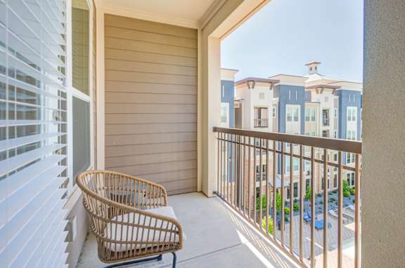 A balcony with a chair and a railing overlooking a building.