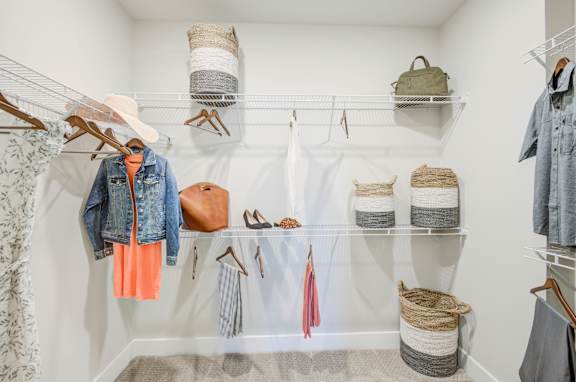 A closet with clothes and bags on shelves and hangers.