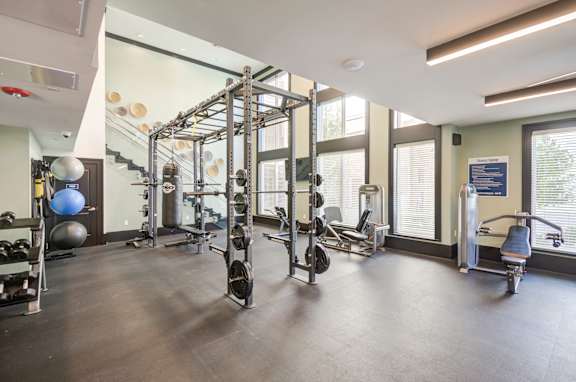A gym with a variety of equipment including a weight rack, a leg press machine, and a rowing machine.