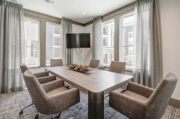 A conference room with a table, chairs, and a television.